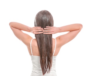 Young woman applying mask onto hair against white background