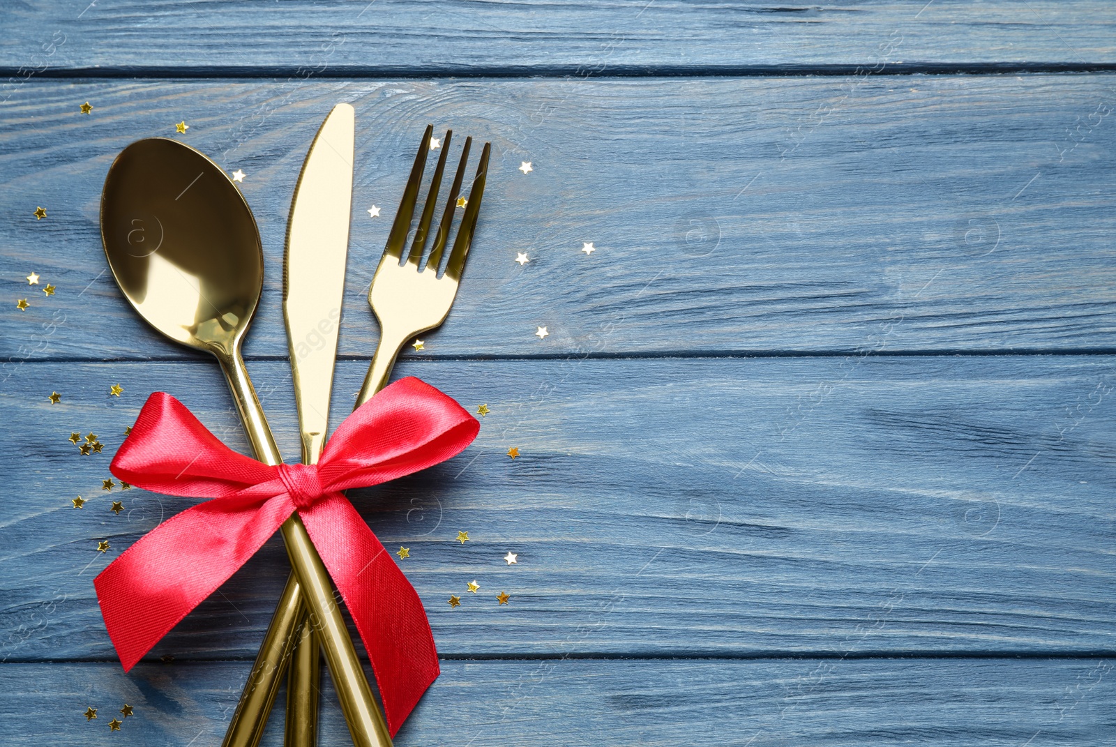 Photo of Cutlery set on blue wooden table, top view with space for text. Christmas celebration