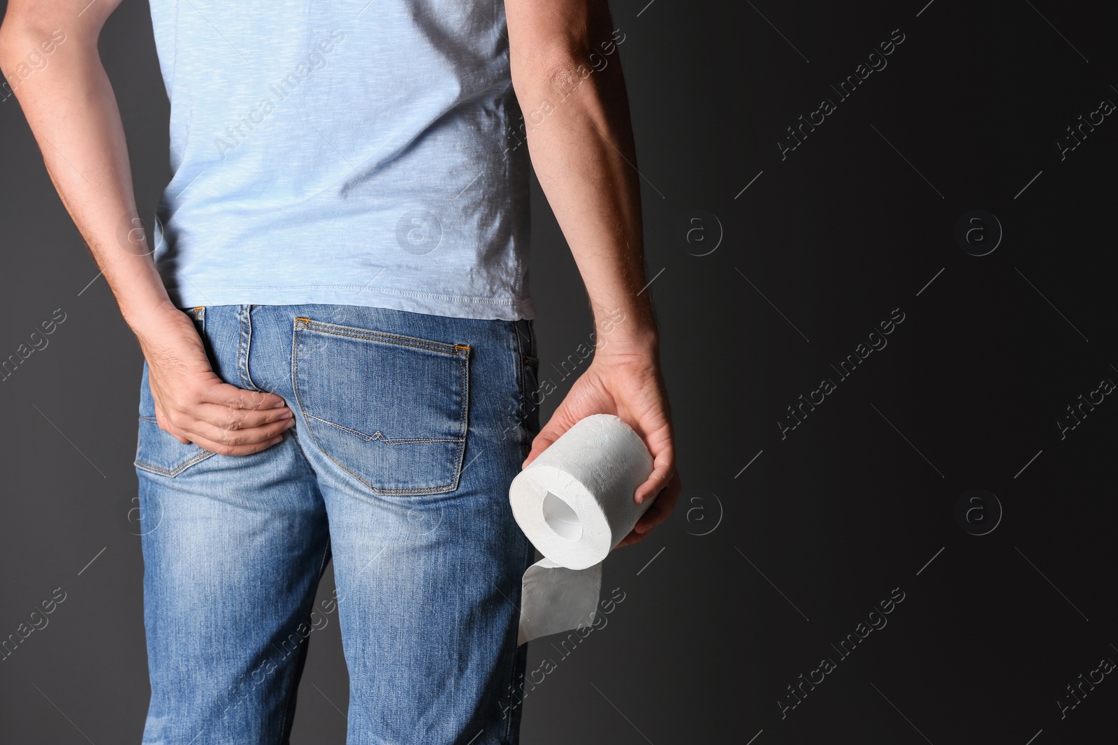 Photo of Man with toilet paper suffering from hemorrhoid on black background, closeup. Space for text