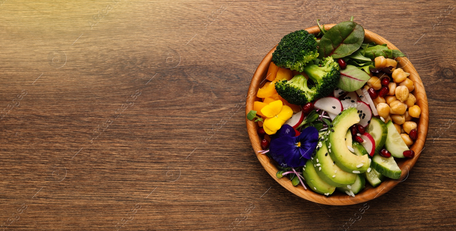 Image of Delicious vegan bowl with broccoli, avocado and cucumber on wooden table, top view. Banner design with space for text