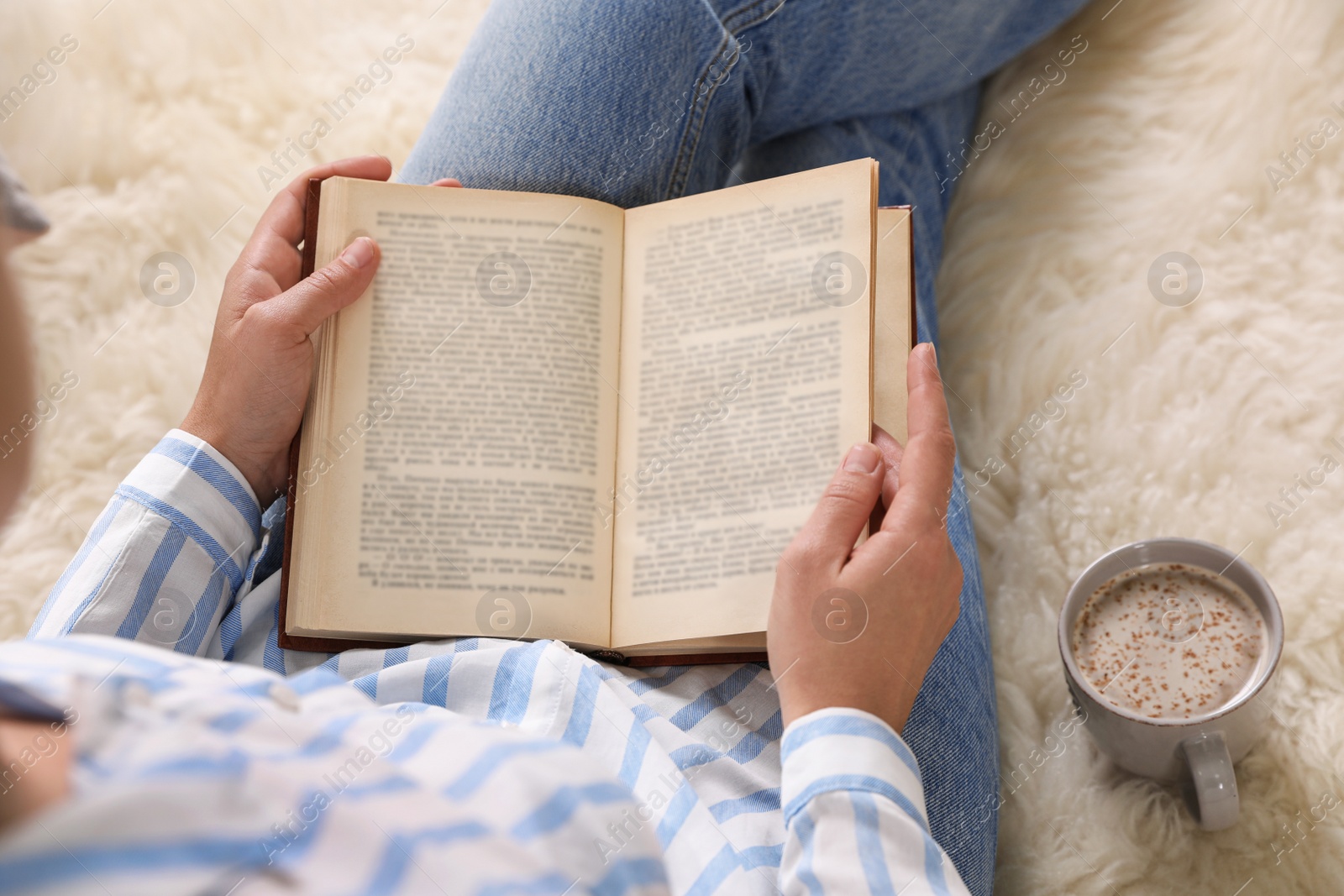 Photo of Woman reading book on fuzzy rug, above view