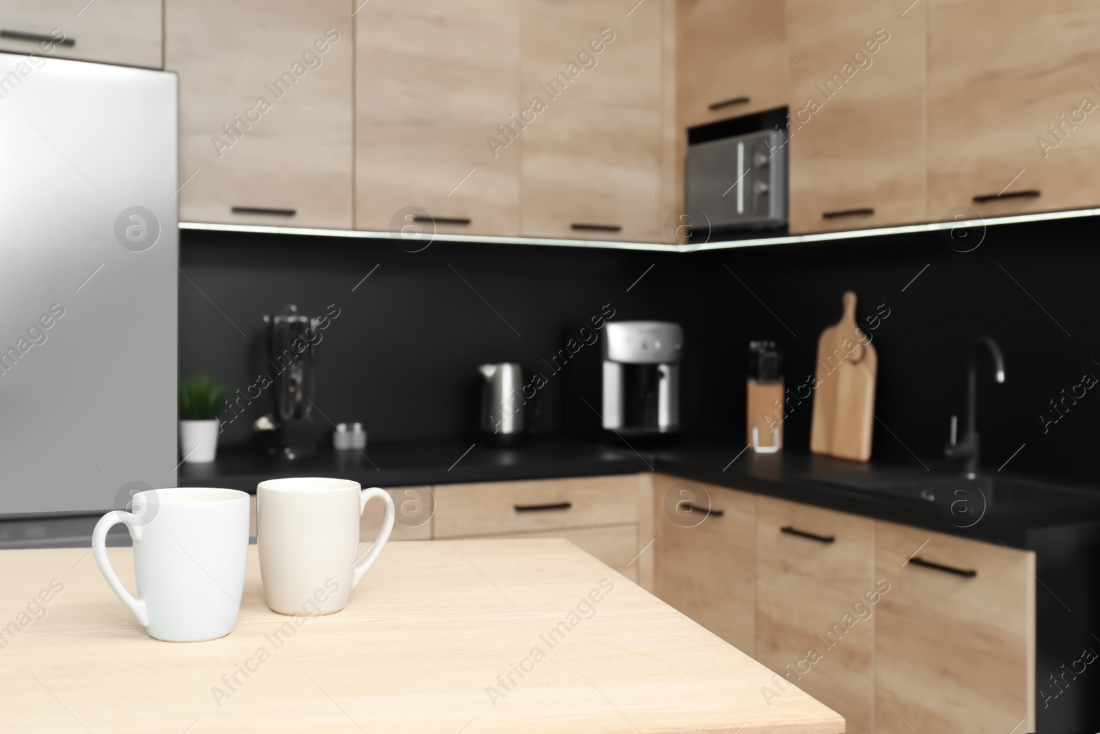 Photo of Cups on table in cozy modern kitchen interior, selective focus