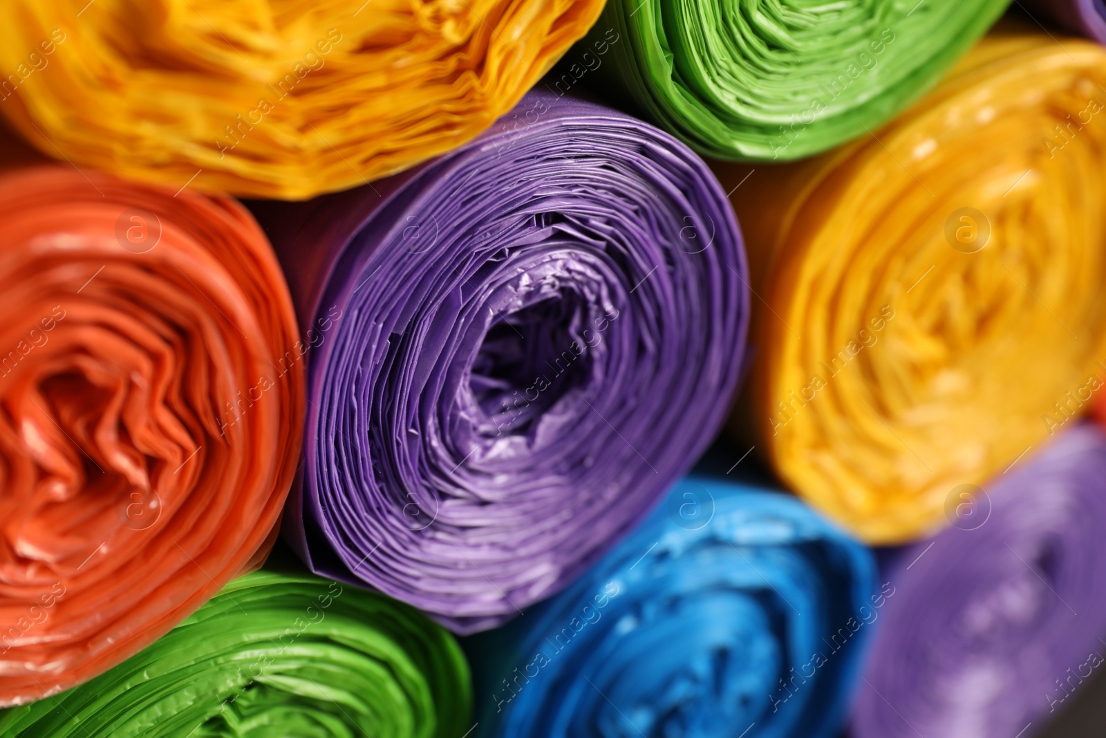 Photo of Rolls of different garbage bags as background, closeup