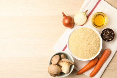 Photo of Flat lay composition with different ingredients on wooden table, space for text. Risotto recipe