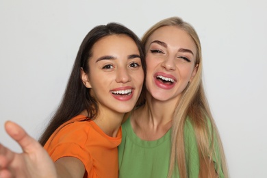 Photo of Young women laughing together against light background