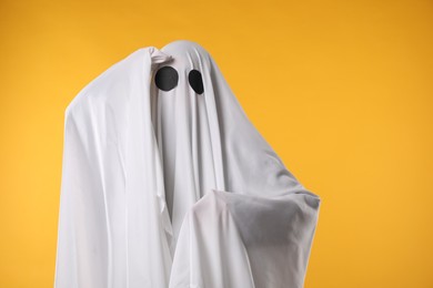 Creepy ghost. Person covered with white sheet on yellow background