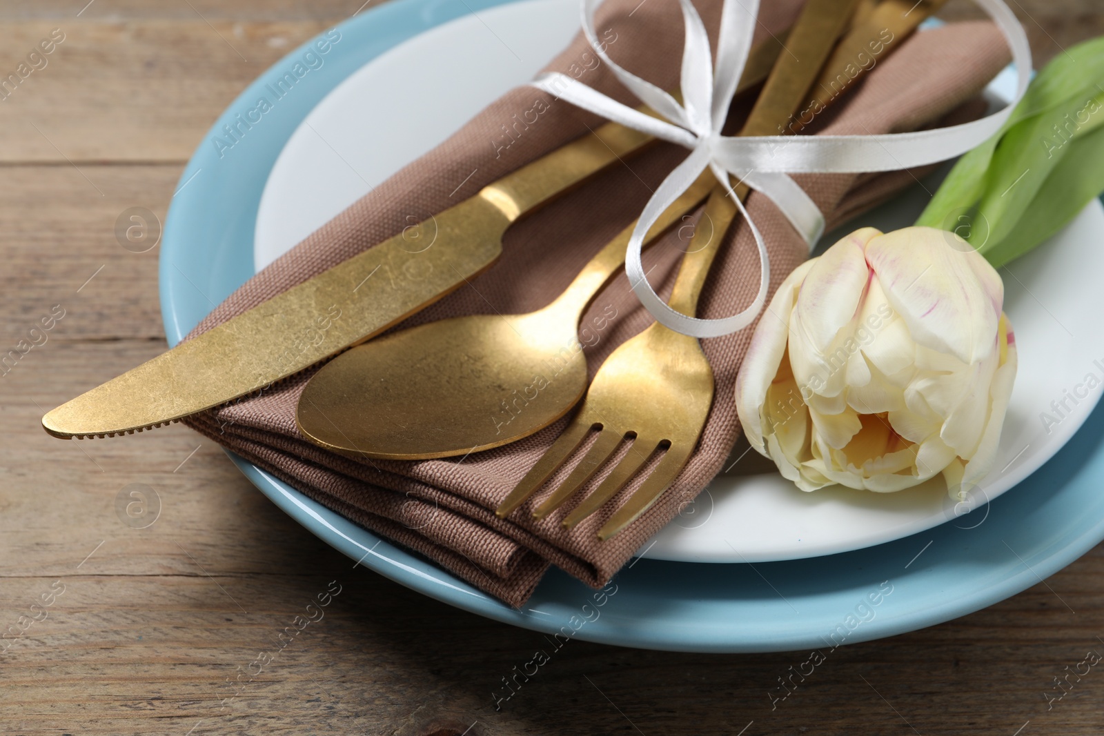 Photo of Stylish table setting with cutlery and tulip on wooden background, closeup