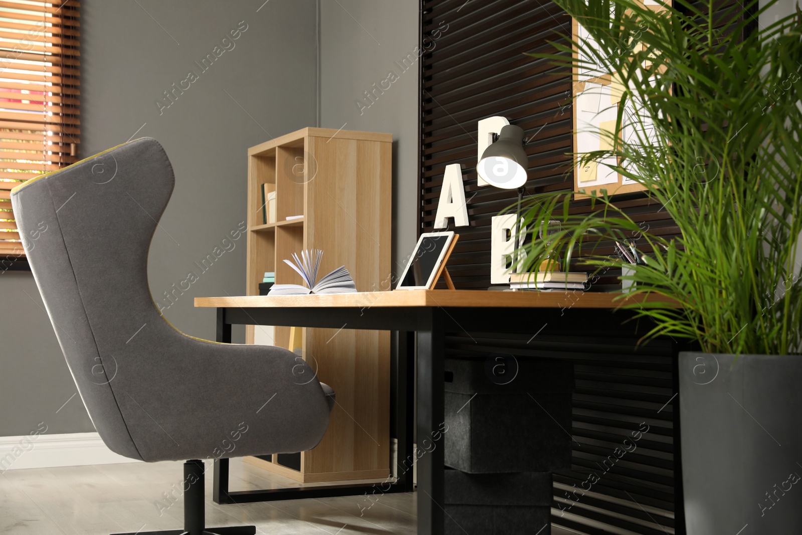 Photo of Comfortable workplace with wooden table and armchair