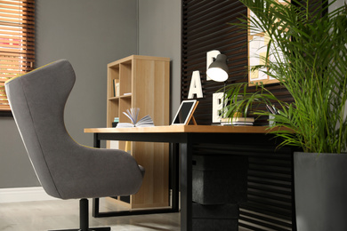 Photo of Comfortable workplace with wooden table and armchair