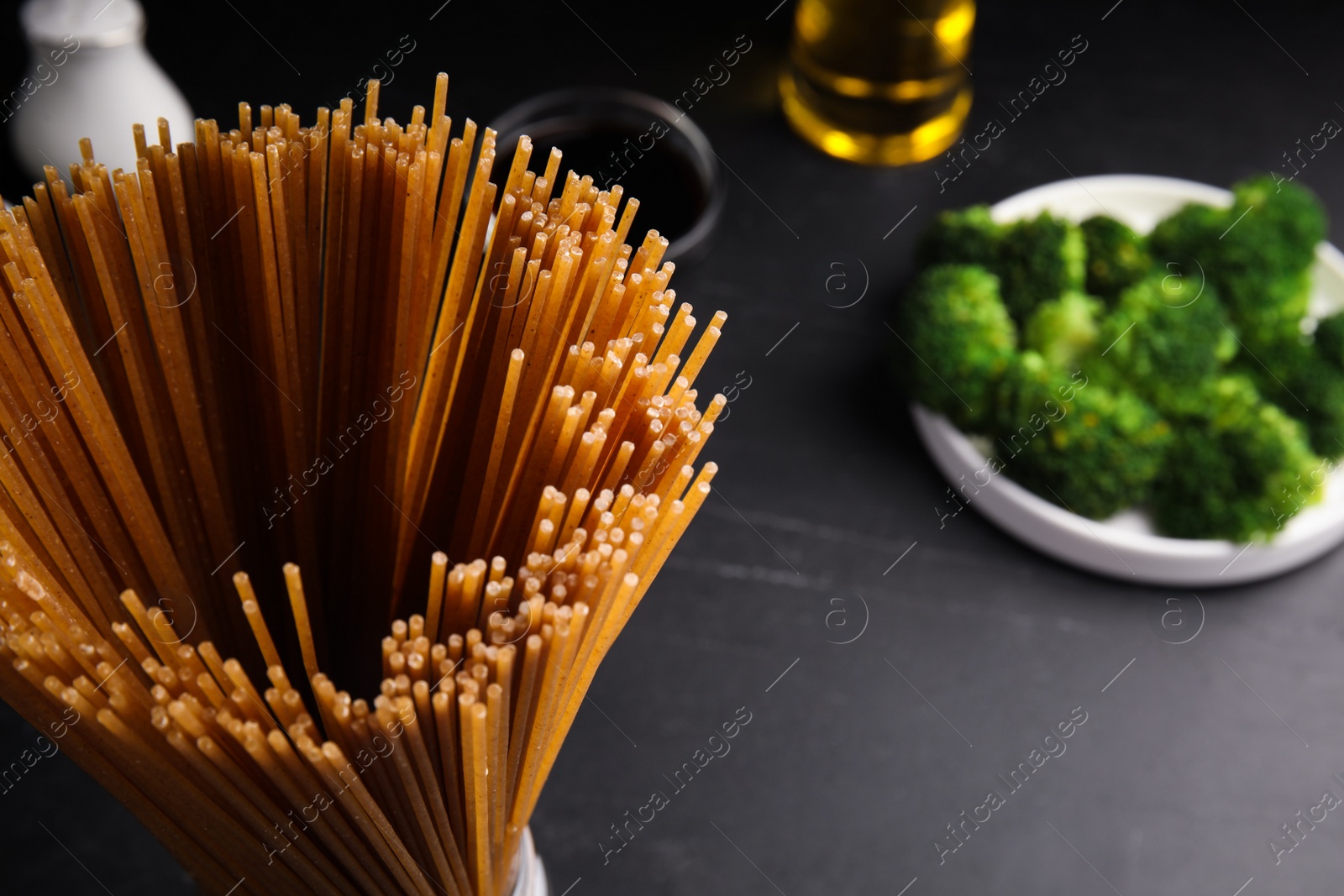 Photo of Uncooked buckwheat noodles on black table, closeup