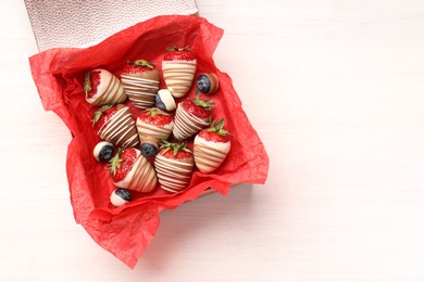 Photo of Box with delicious chocolate covered strawberries and blueberries on white table, top view. Space for text