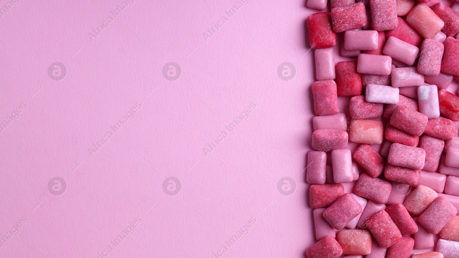 Photo of Many sweet chewing gums on pink background, flat lay