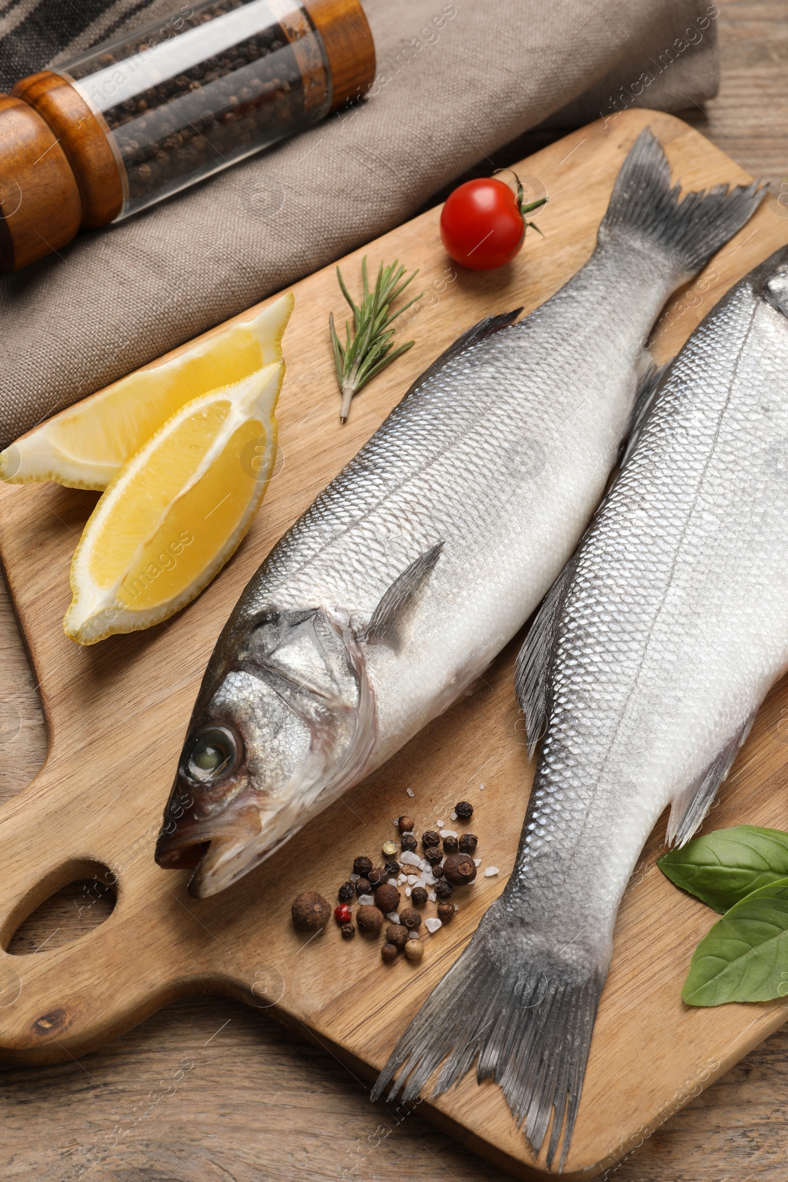 Photo of Sea bass fish and ingredients on wooden table, closeup