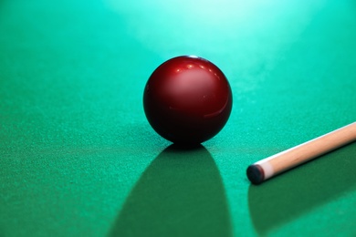 Red billiard ball and cue on table