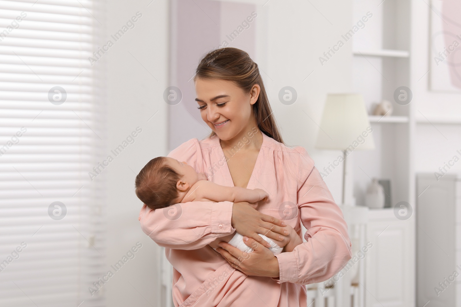 Photo of Mother holding her cute newborn baby in child's room