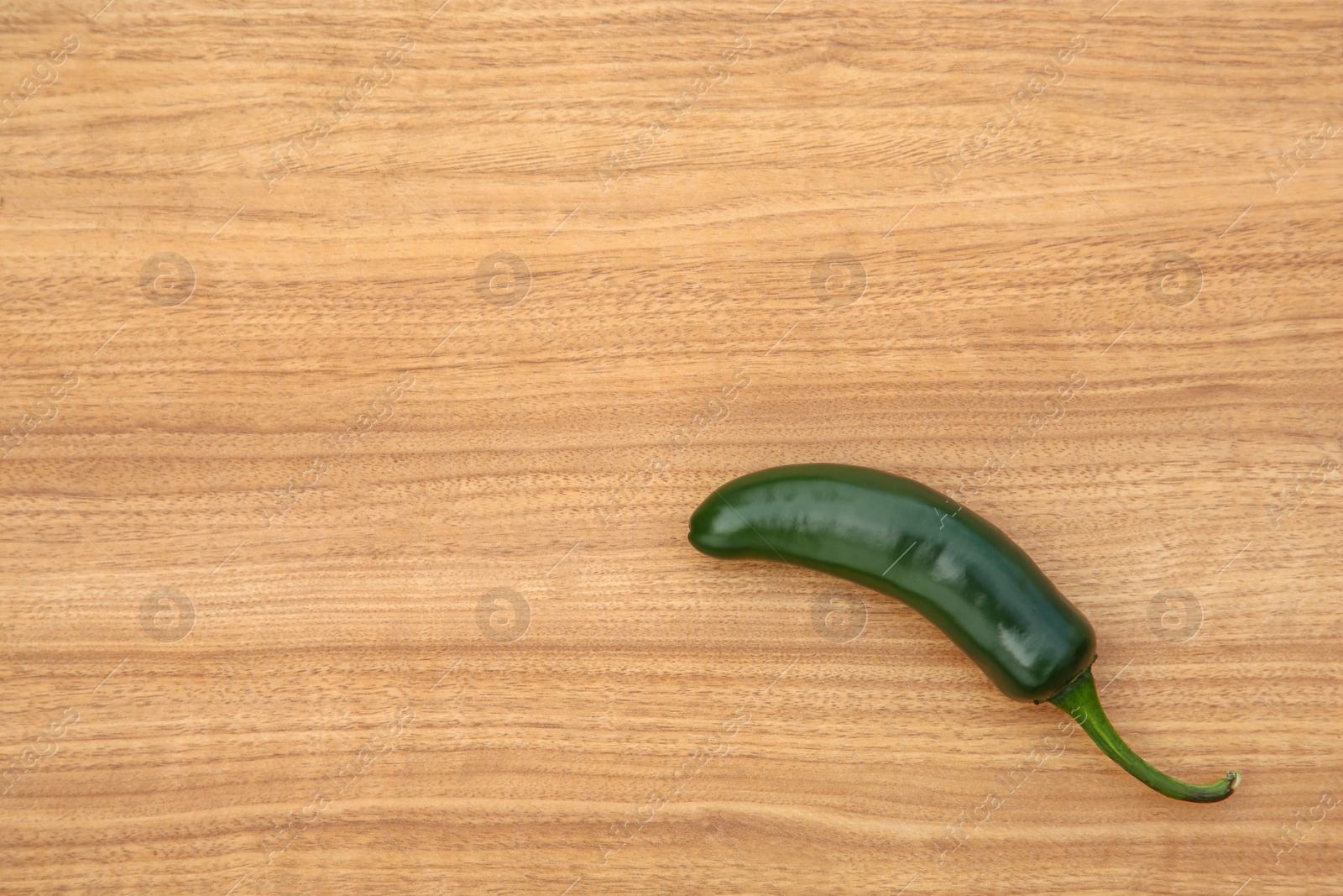 Photo of Fresh green jalapeno pepper on wooden table, top view. Space for text