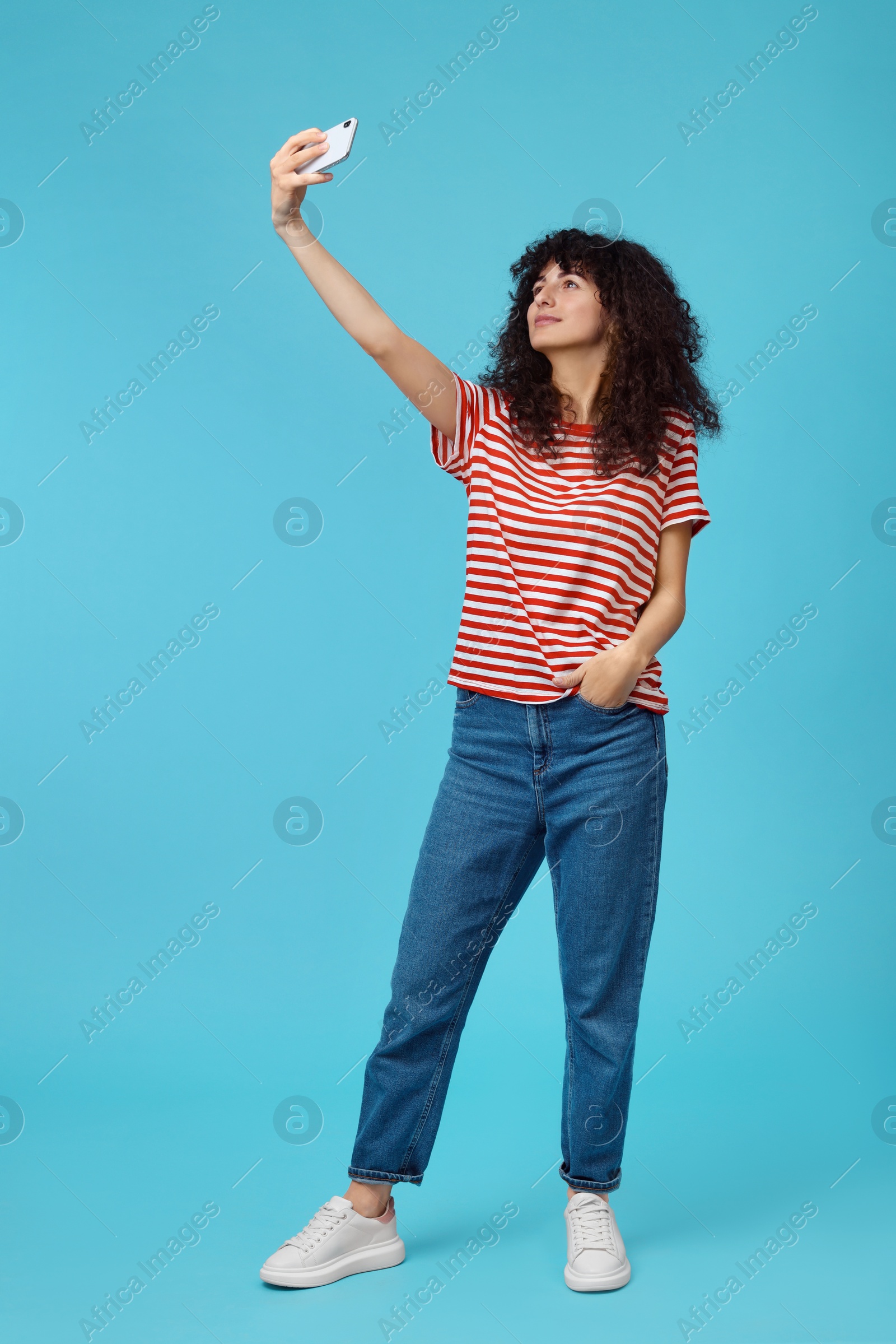 Photo of Beautiful young woman taking selfie on light blue background