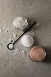 Photo of Different natural salt on grey textured table, flat lay