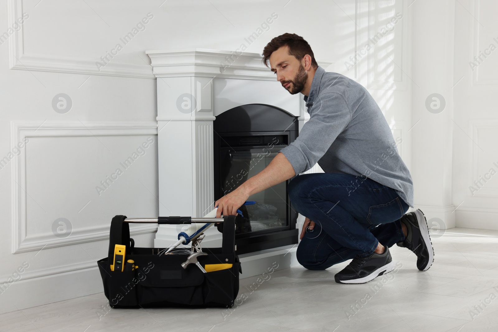 Photo of Man installing electric fireplace near white wall in room