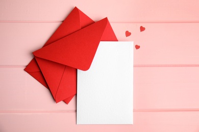 Envelopes and blank card on pink wooden table, flat lay. Love letters