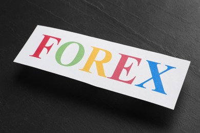 Photo of Sheet of paper with word Forex on black table, closeup