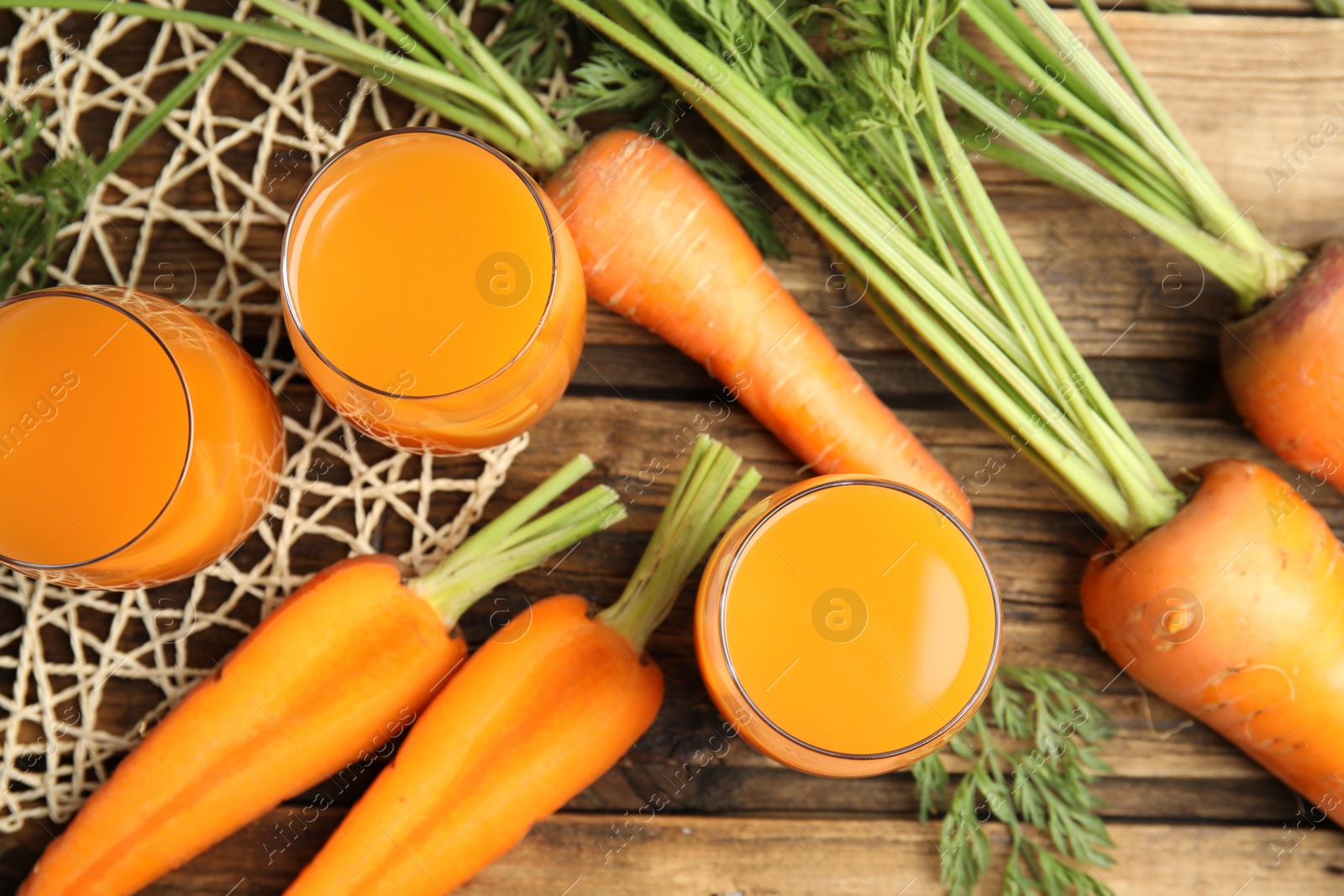 Photo of Freshly made carrot juice on wooden table, flat lay