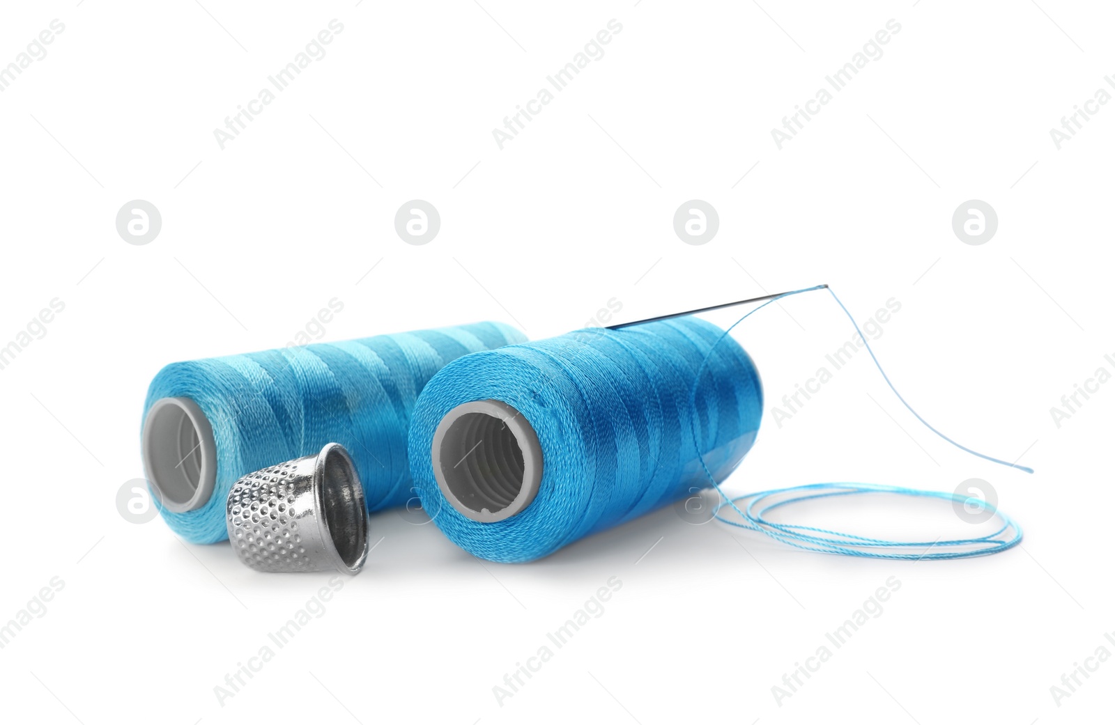 Photo of Color sewing threads, needle and thimble on white background