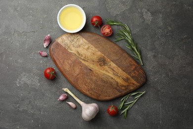 Photo of Cutting board, rosemary, garlic, oil and tomatoes on black table, flat lay. Space for text