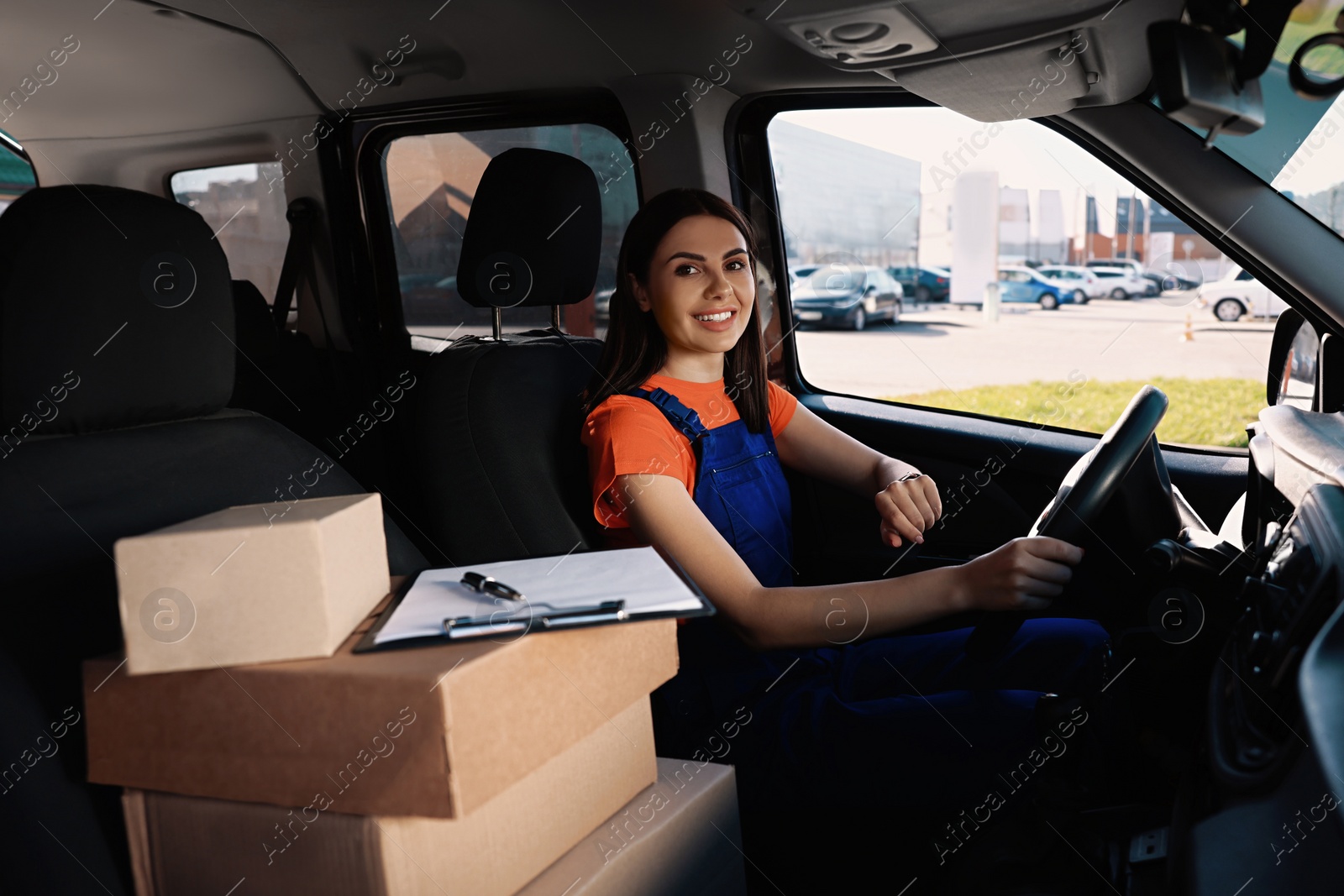 Photo of Courier with clipboard and parcels in car. Delivery service