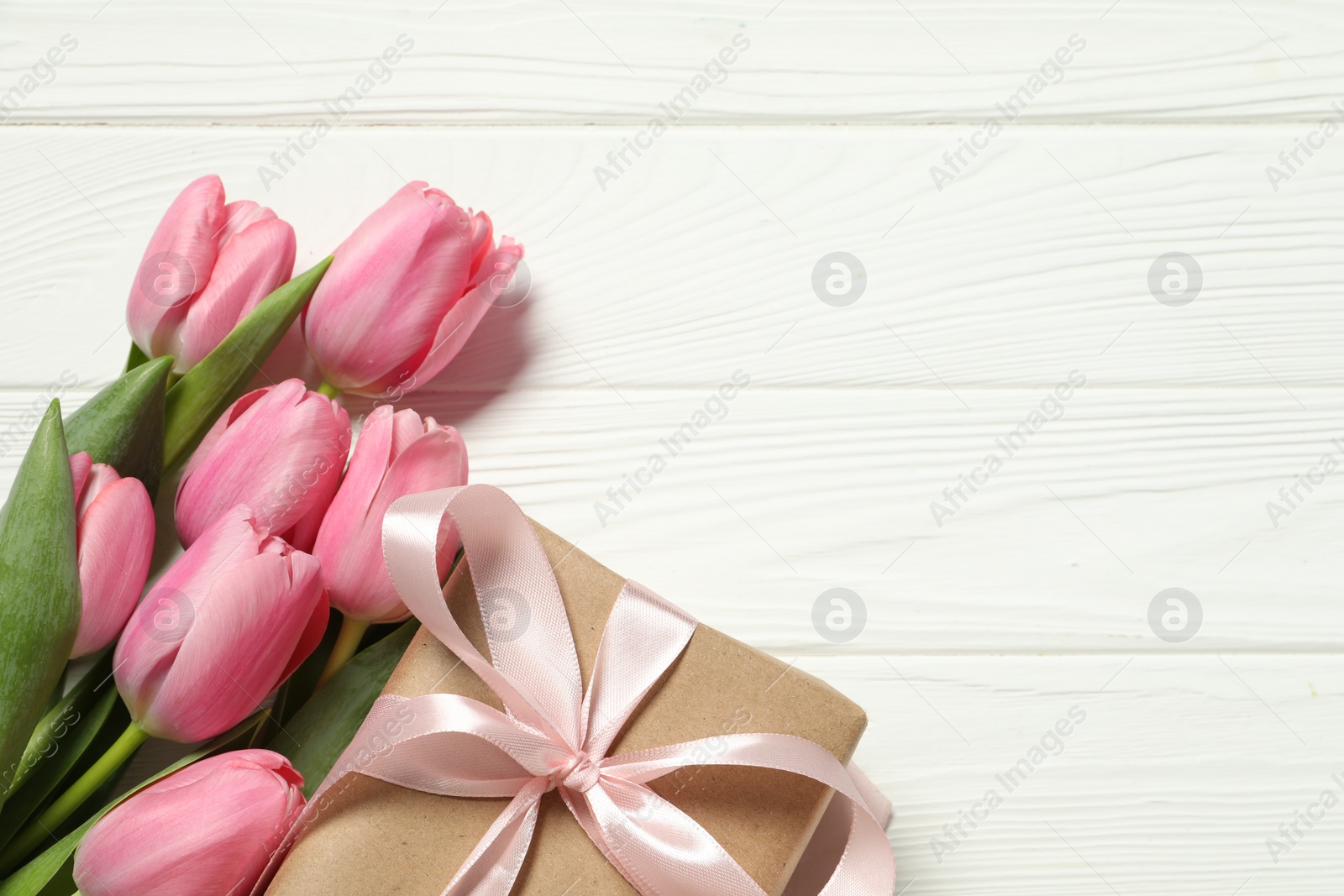 Photo of Happy Mother's Day. Beautiful pink tulips and gift box on white wooden table, flat lay. Space for text