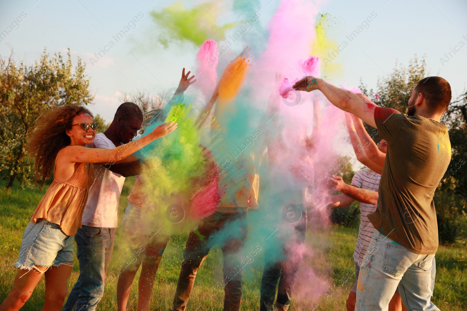 Photo of Happy friends having fun with colorful powder dyes outdoors. Holi festival celebration