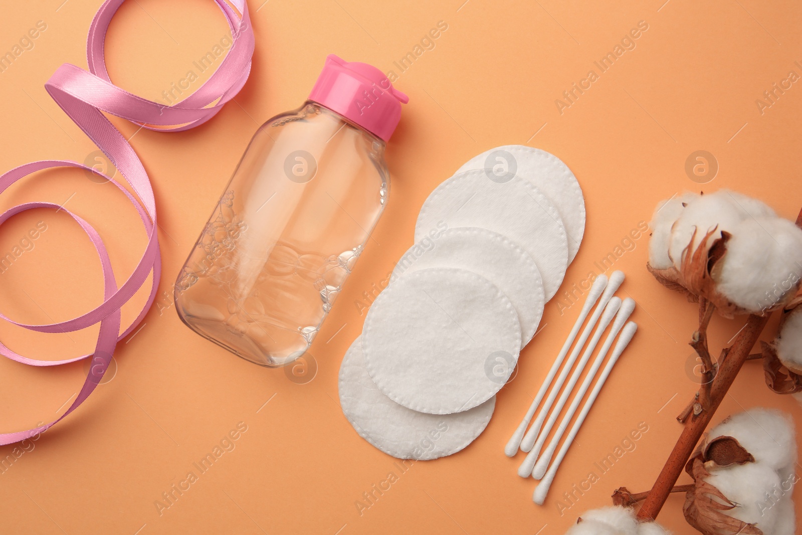 Photo of Flat lay composition with makeup remover and cotton flowers on pale orange background