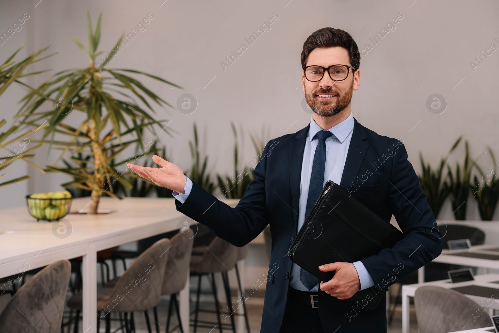 Photo of Happy real estate agent with leather portfolio in office