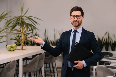 Happy real estate agent with leather portfolio in office