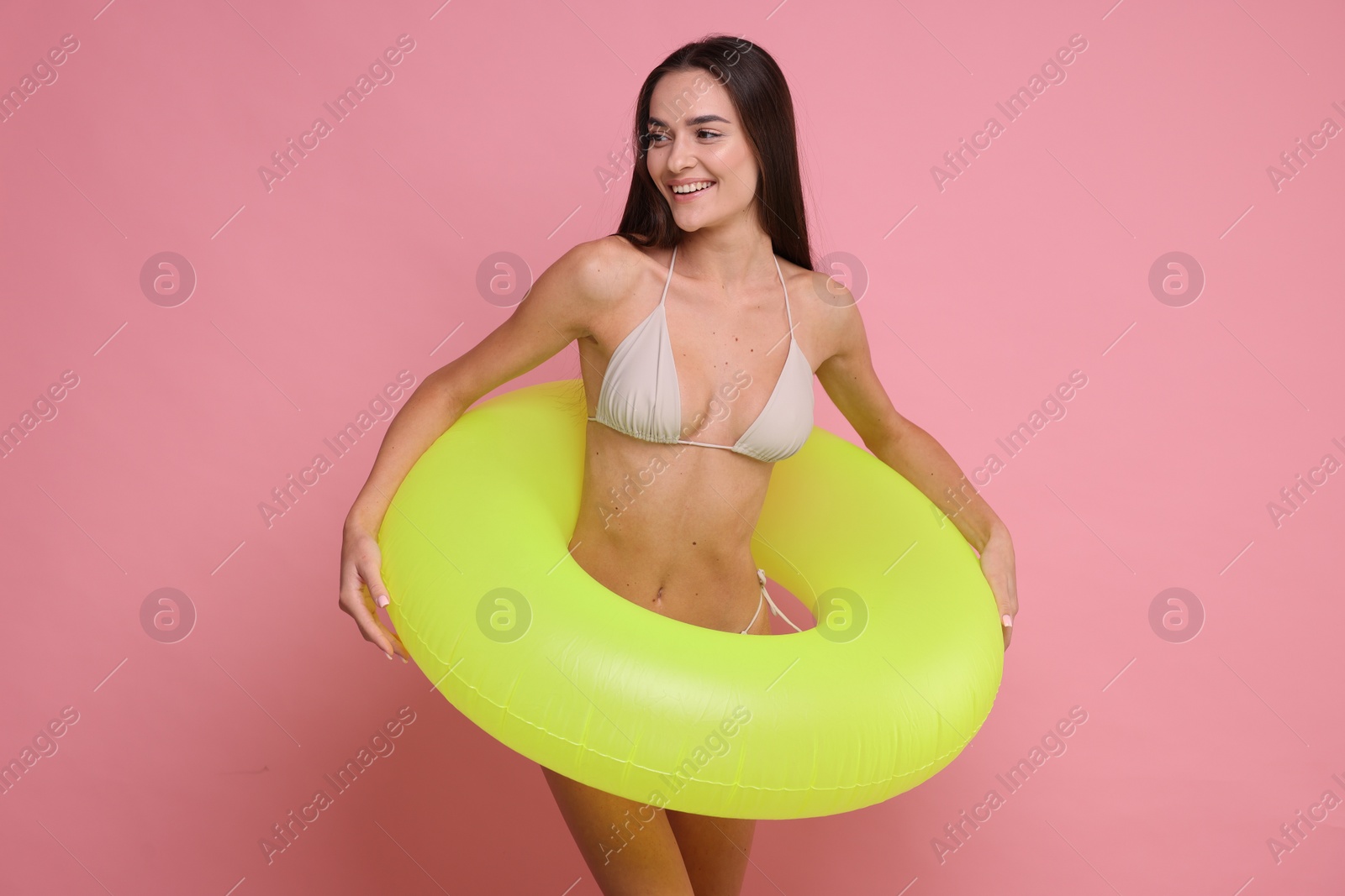 Photo of Young woman in stylish bikini with inflatable ring on pink background