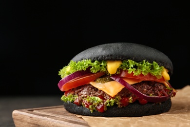 Photo of Board with black burger on table, closeup