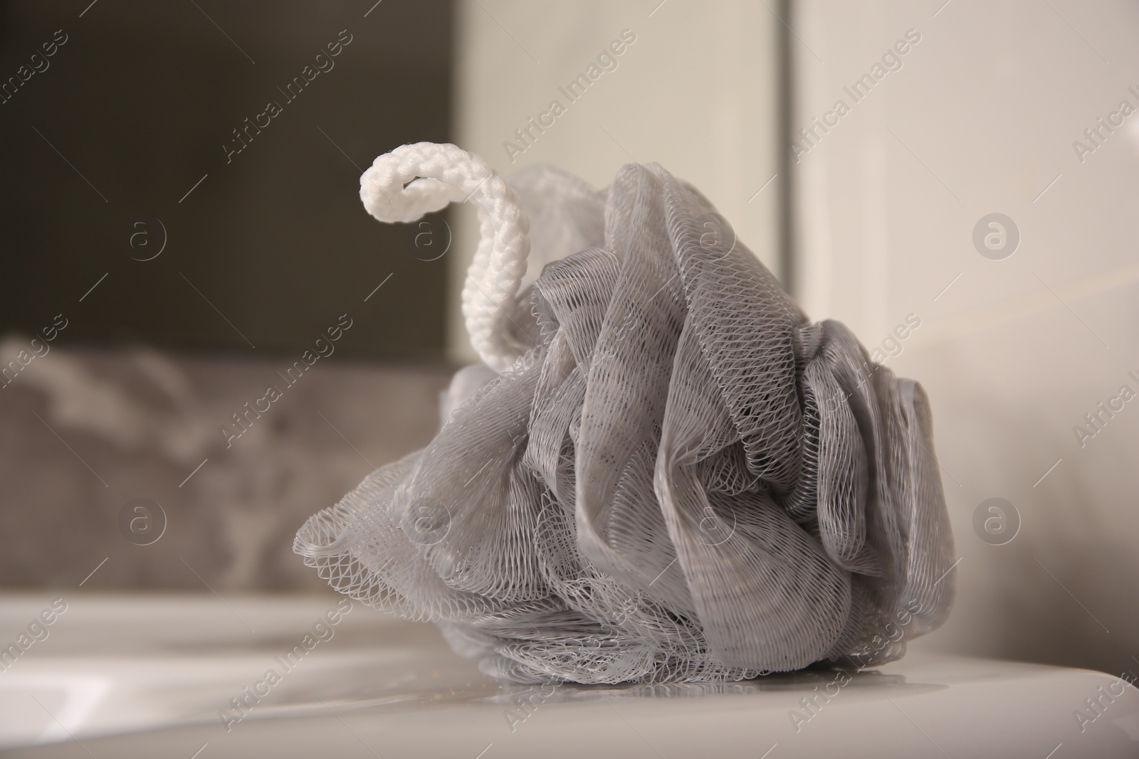 Photo of Grey shower puff on washbasin in bathroom, closeup