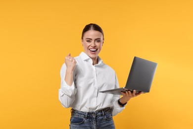 Photo of Happy woman with laptop on orange background