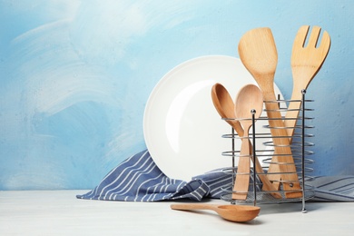 Photo of Plate, napkin and holder with wooden kitchen utensils on table. Space for text