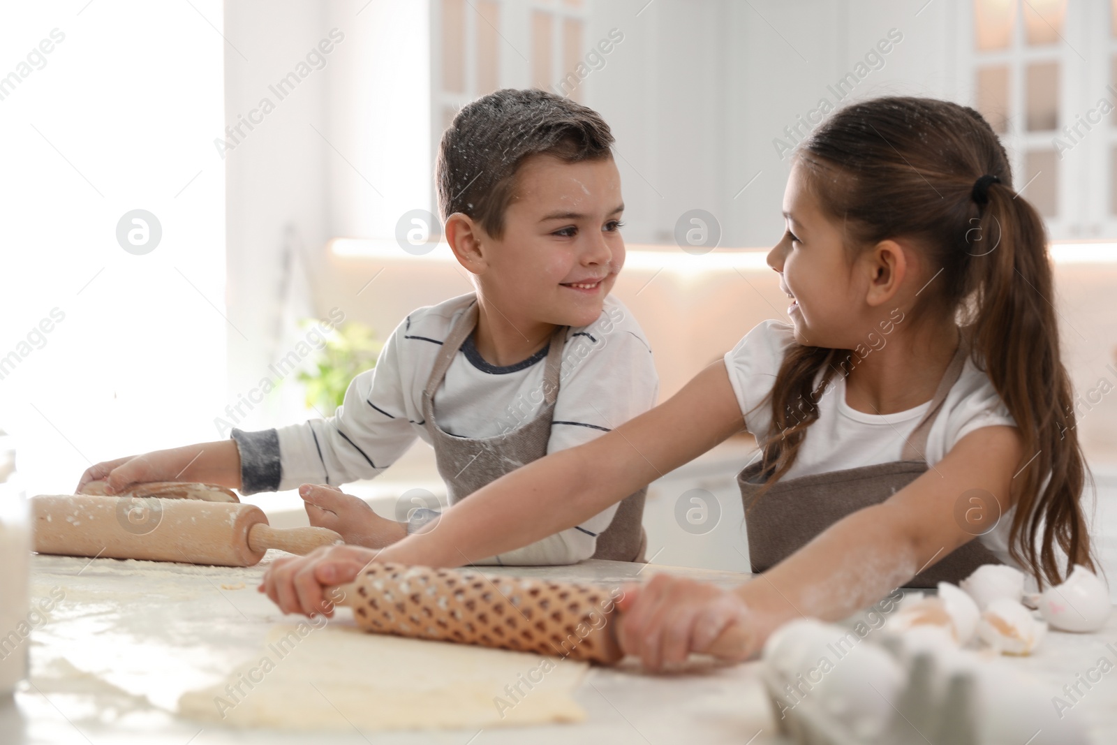 Photo of Cute little children cooking dough together in kitchen