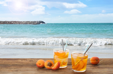 Tasty refreshing drink on wooden table against sea