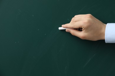 Teacher writing with chalk on green chalkboard, closeup. Space for text