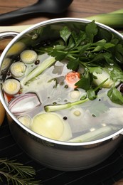 Pot with different ingredients for cooking tasty bouillon on table