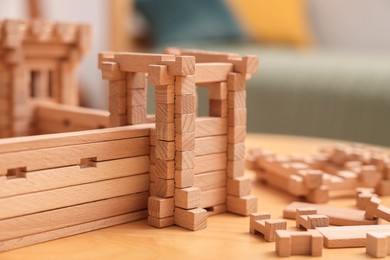 Photo of Wooden fortress and building blocks on table indoors, closeup. Children's toy