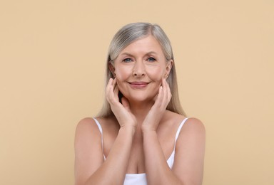 Portrait of beautiful senior woman on beige background. Space for text