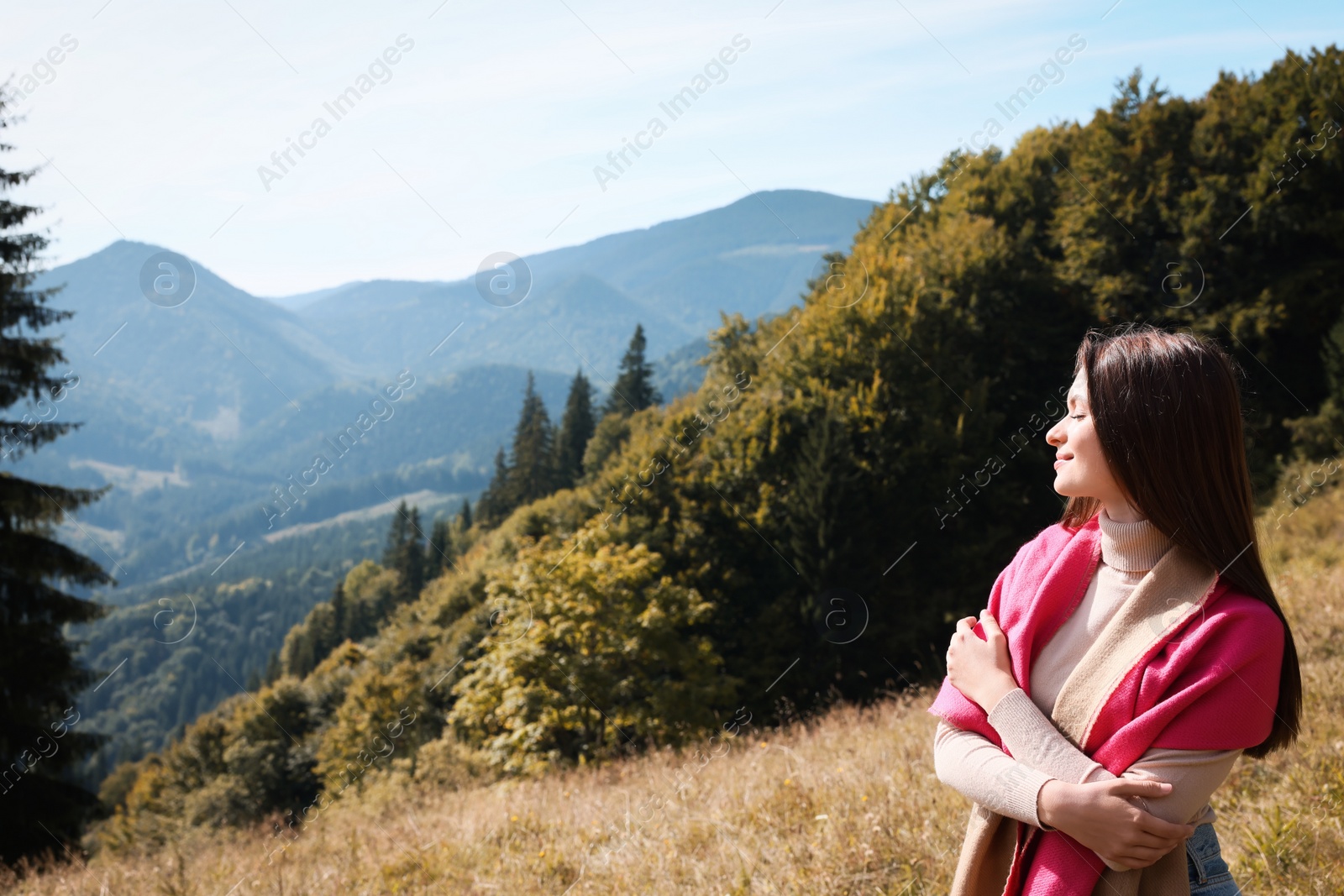 Photo of Young woman in mountains on sunny day, space for text