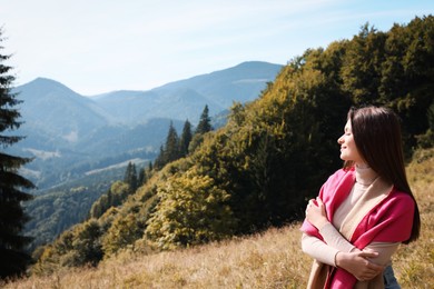 Young woman in mountains on sunny day, space for text