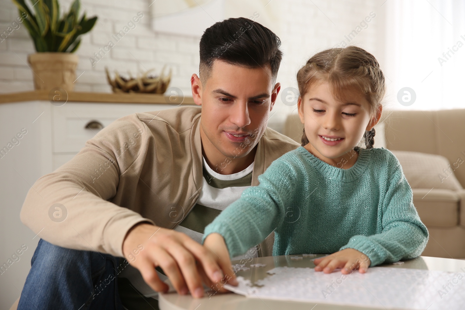 Photo of Happy father and his daughter playing with puzzles at home