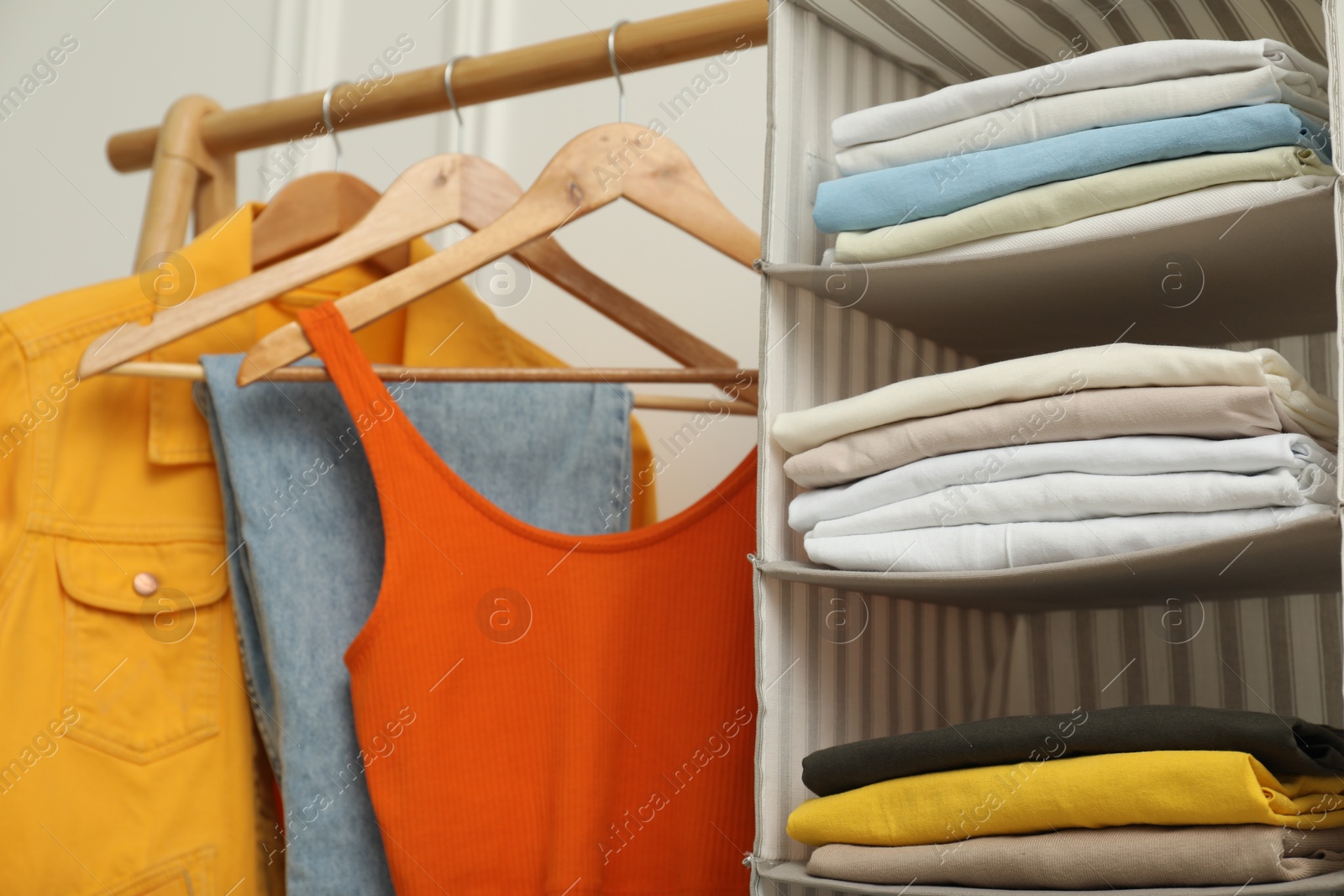 Photo of Wardrobe organization. Rack with different stylish clothes near white wall