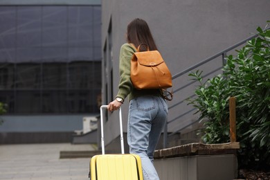 Being late. Woman with backpack and suitcase walking outdoors, back view with space for text